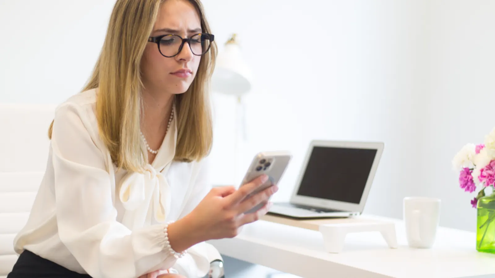 Small business owner checking her phone at a bright desk