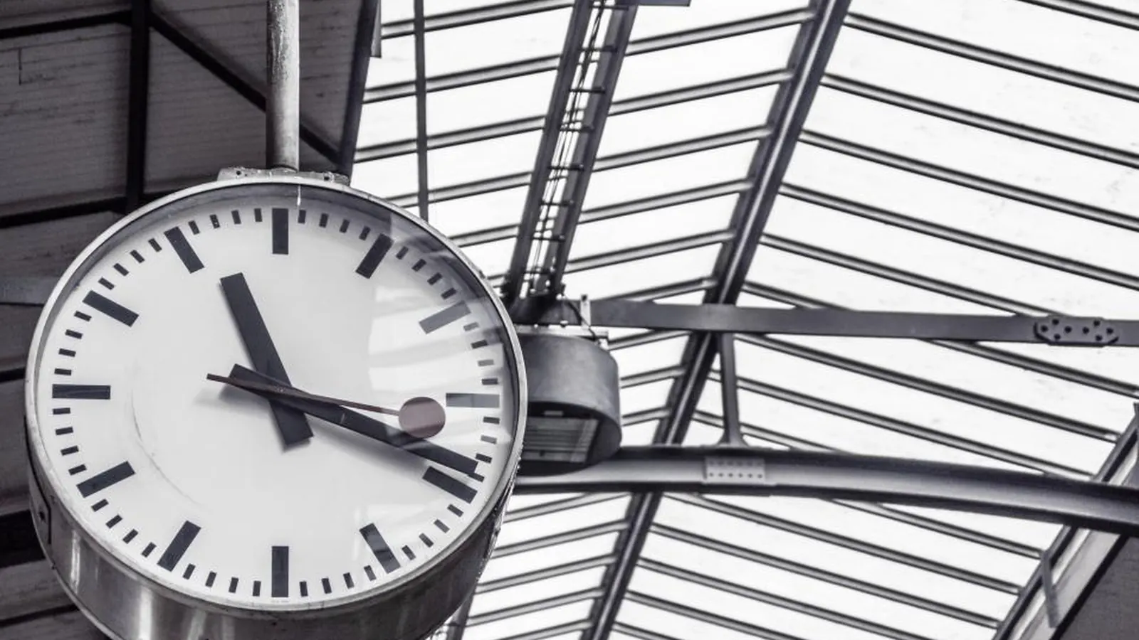 Station clock hanging under a glass roof