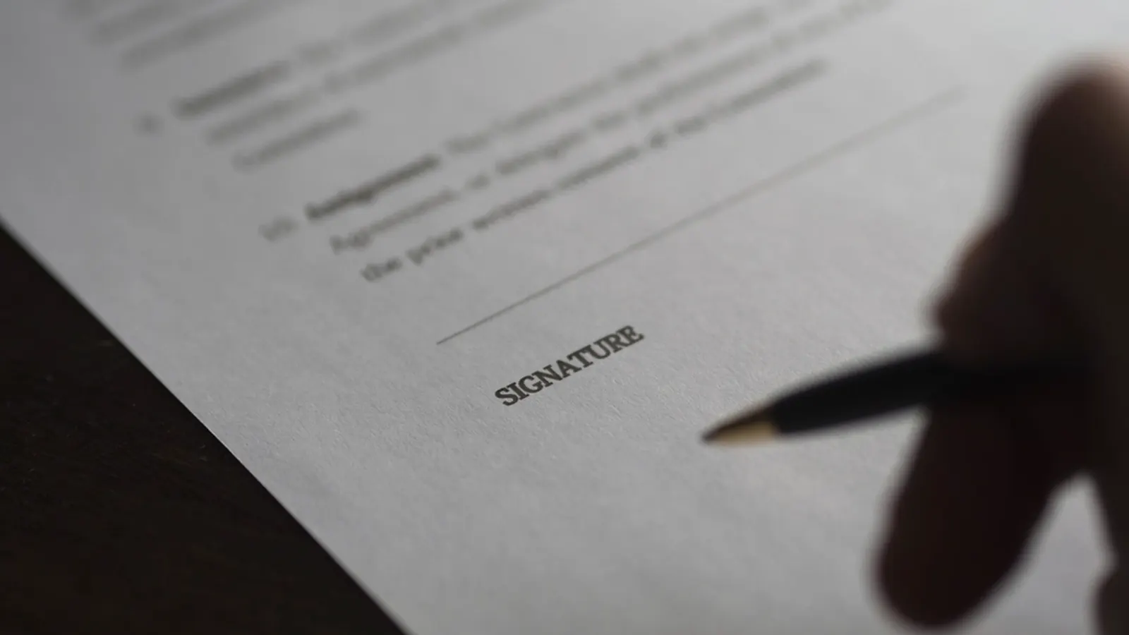 Pen resting on a document beside the signature line