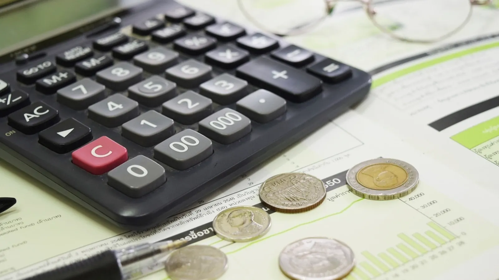 Calculator and coins on top of financial papers