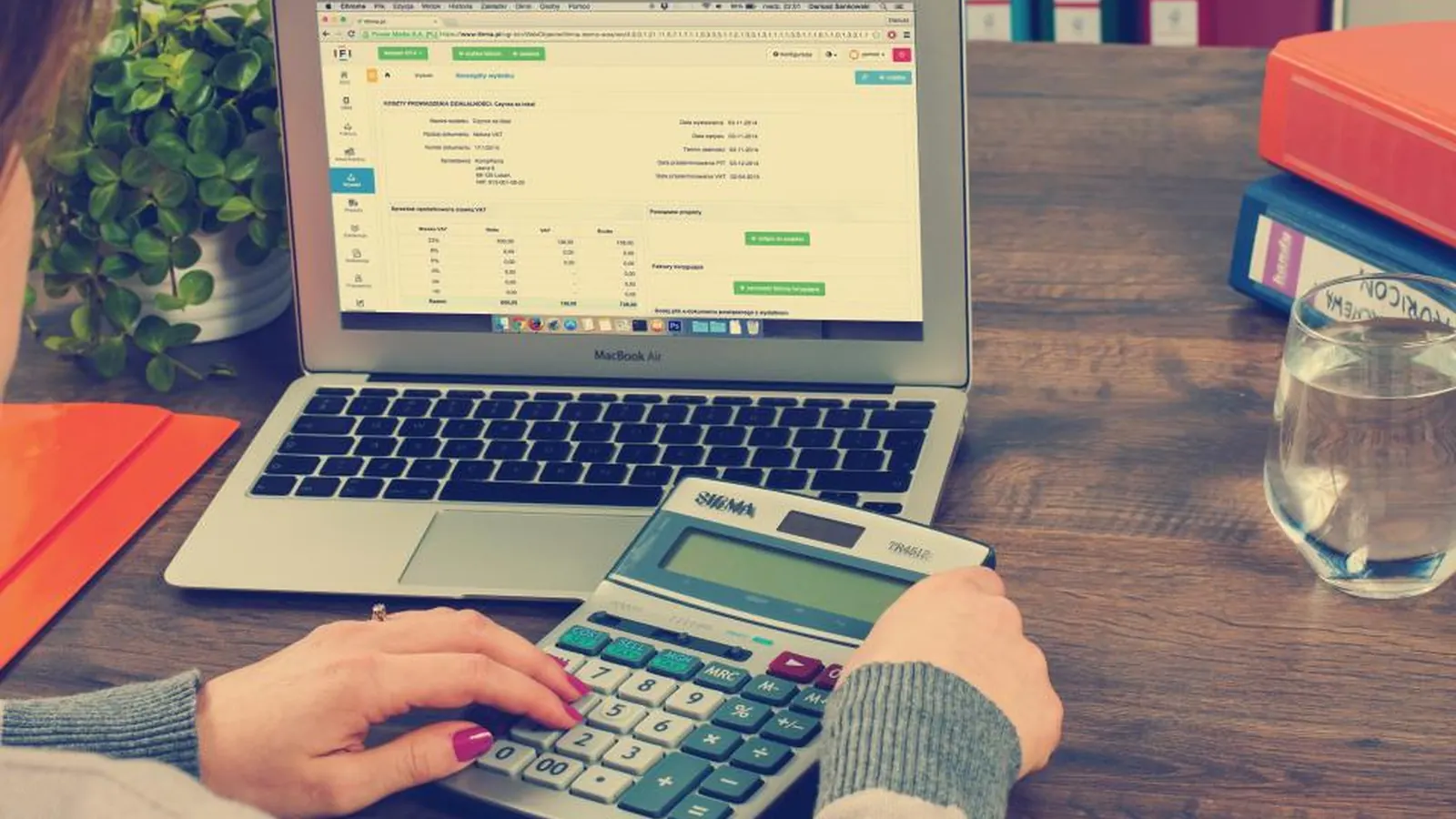 Person using a calculator next to a laptop showing a spreadsheet
