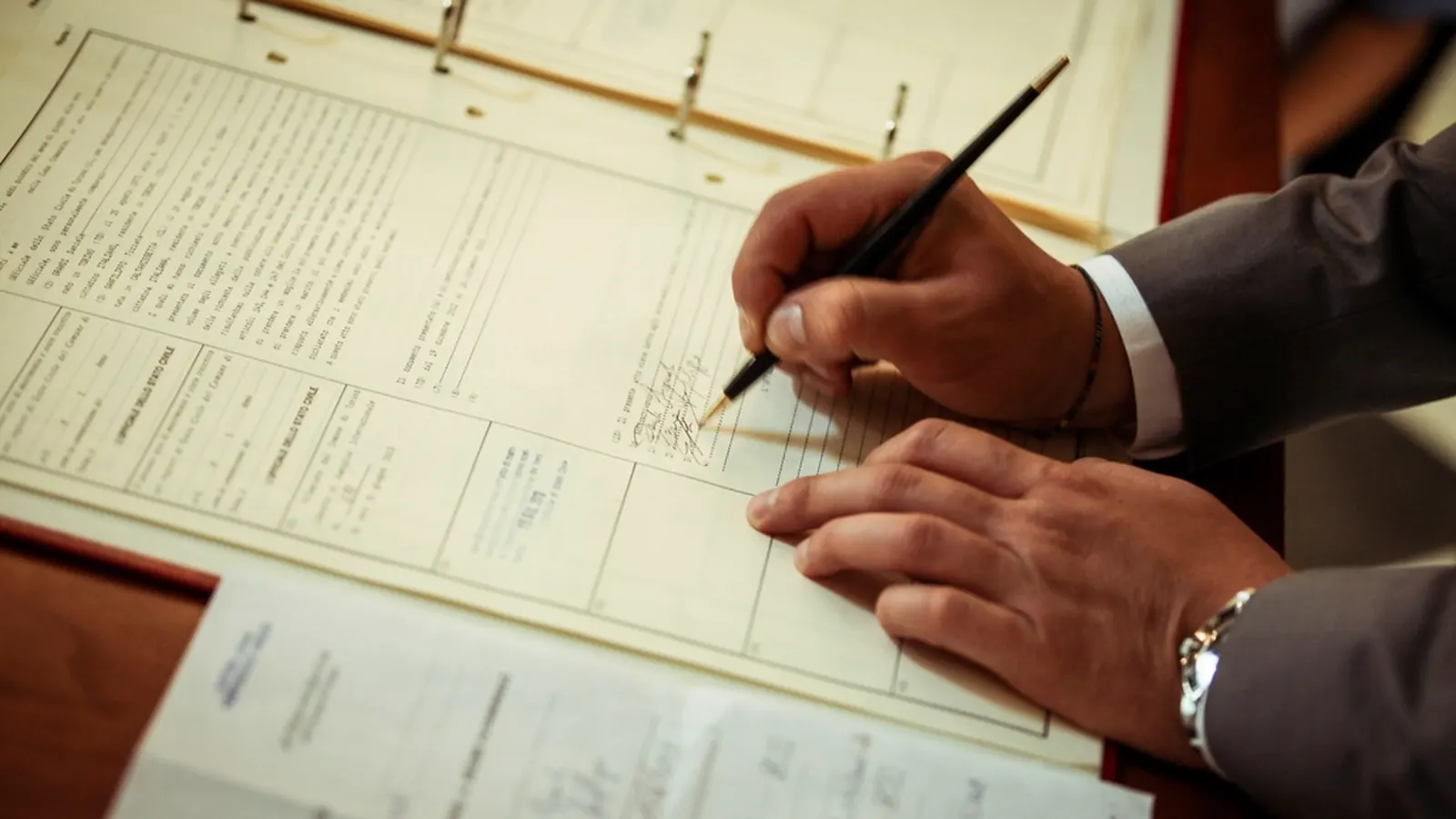 Person filling in a paper form with a pen