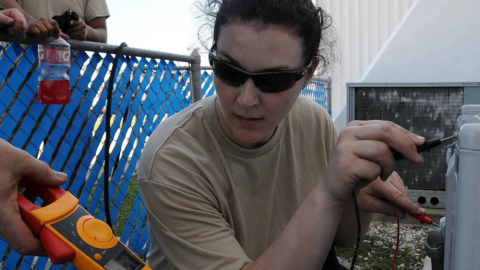 Technician testing an outdoor unit with a clamp meter