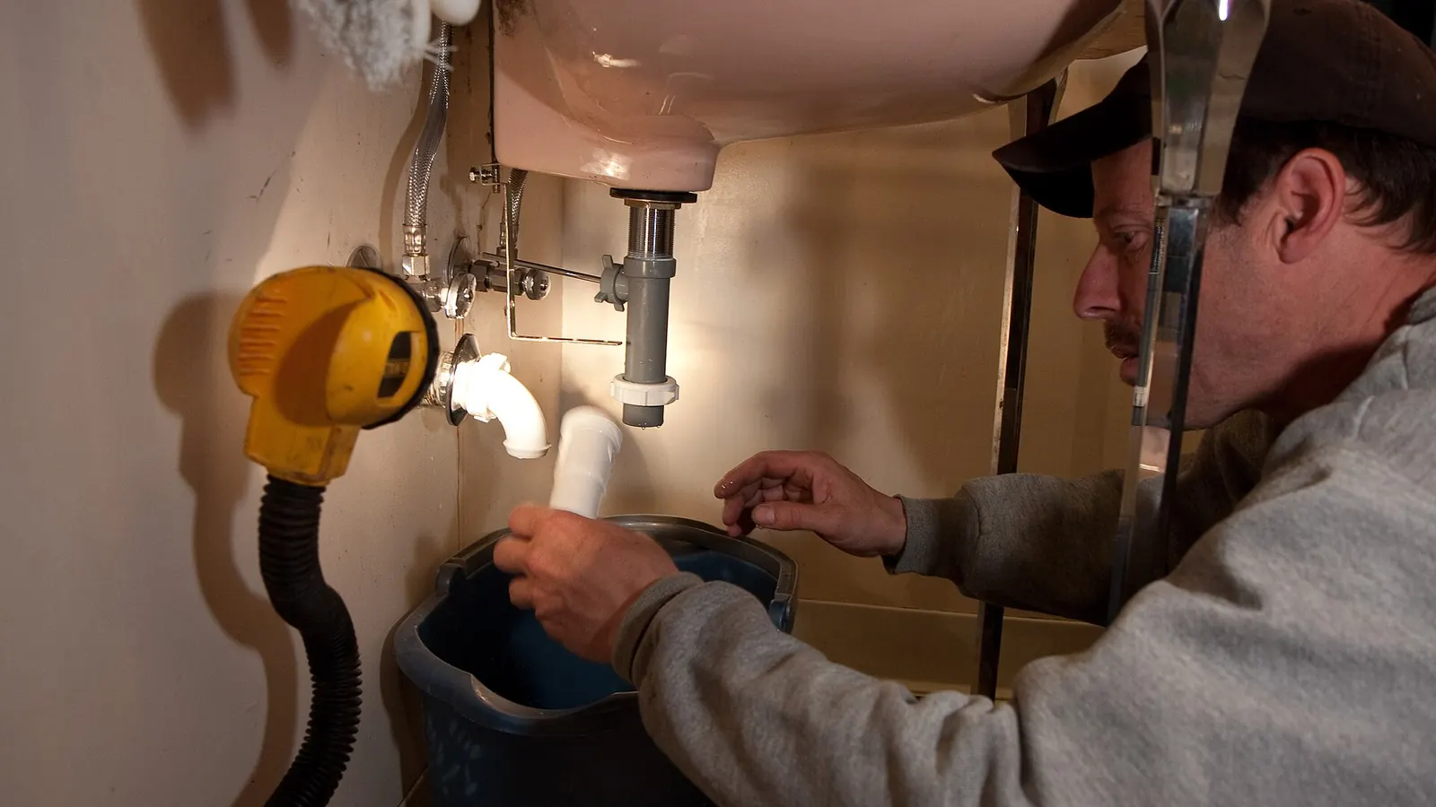 Plumber repairing pipes under a sink