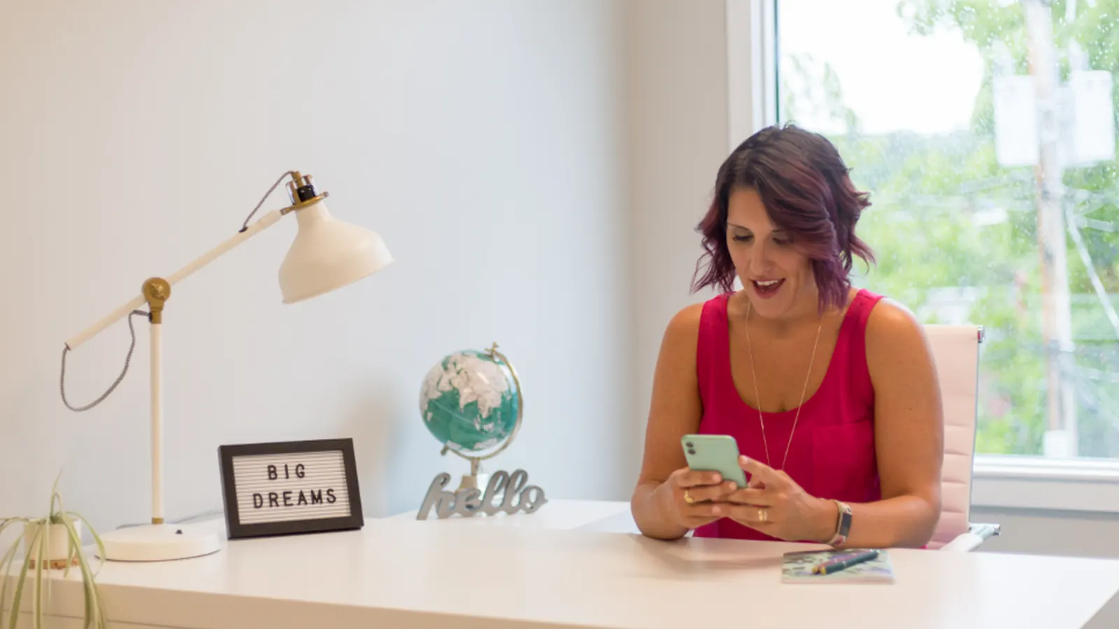 Woman using her phone at a home office desk