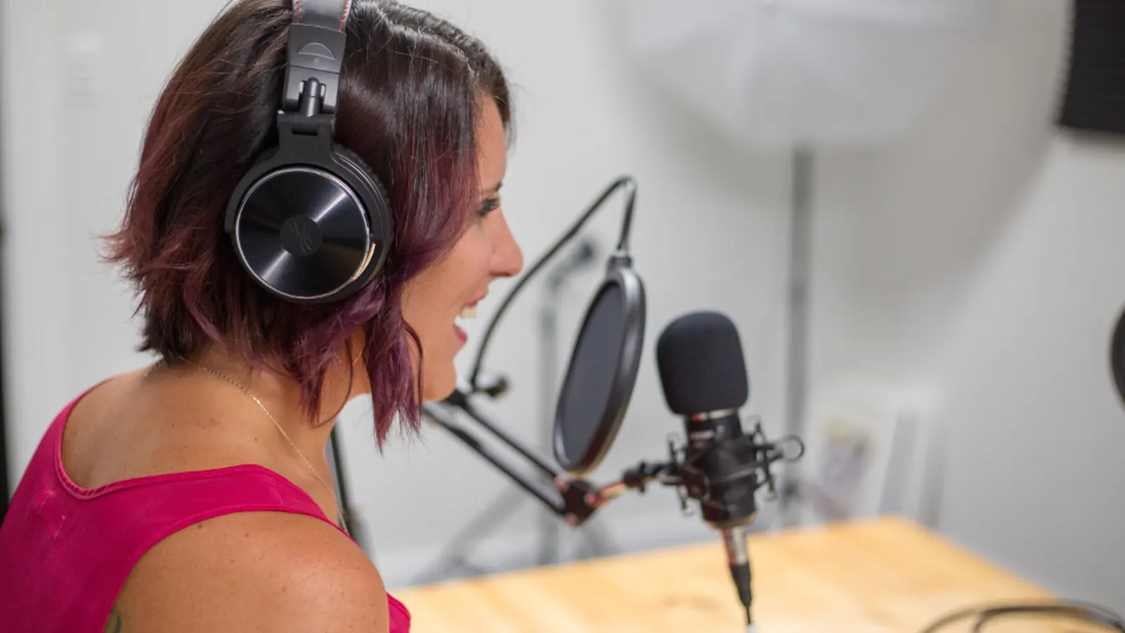 Woman with headphones speaking into a studio microphone
