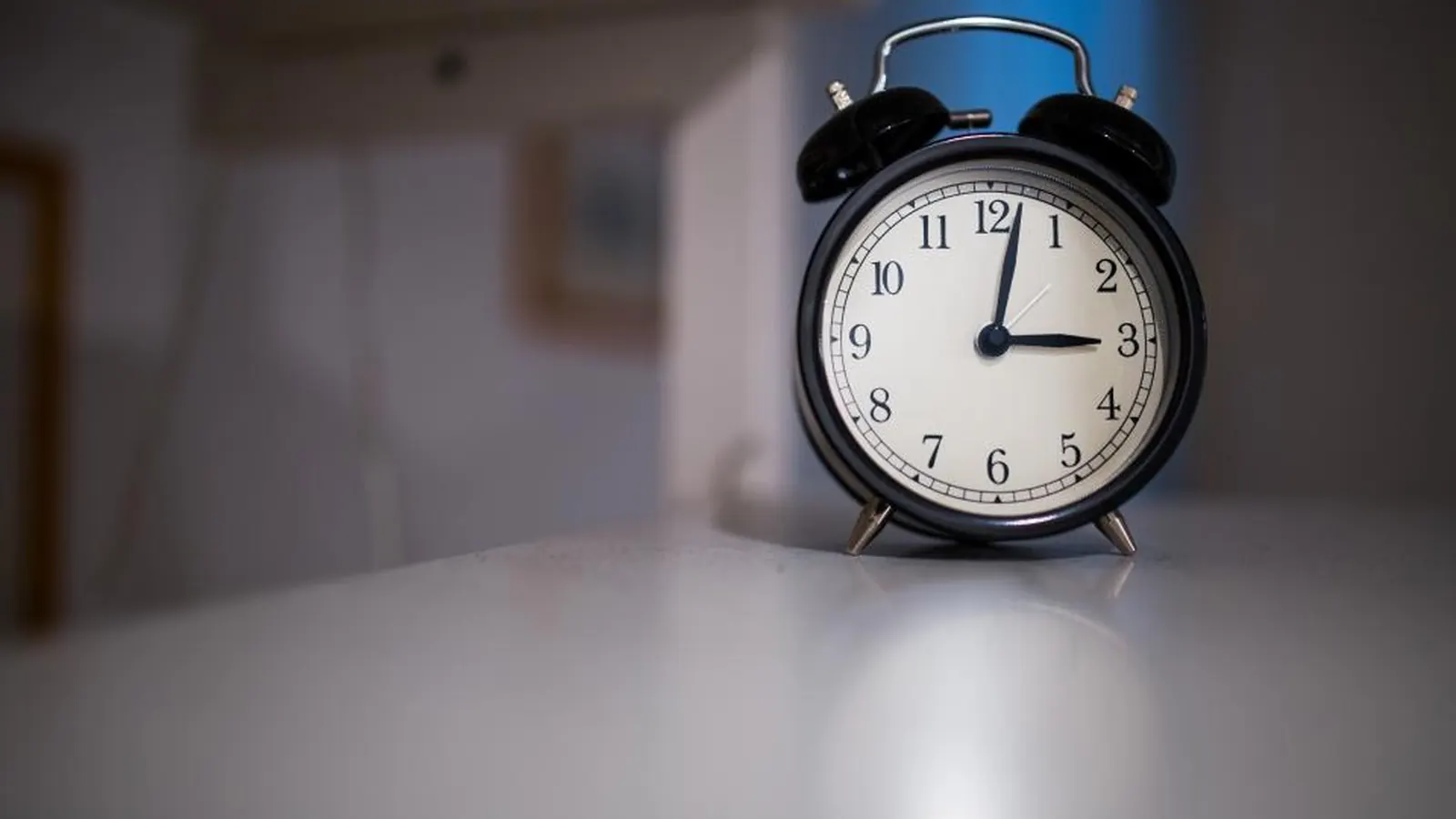 Alarm clock on a table showing a few minutes past twelve