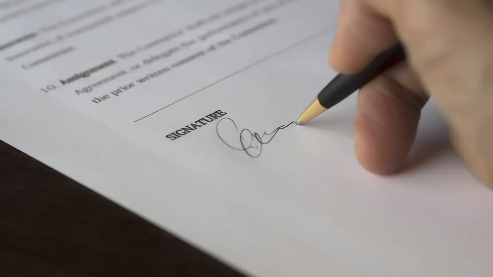 Hand signing a contract with a pen