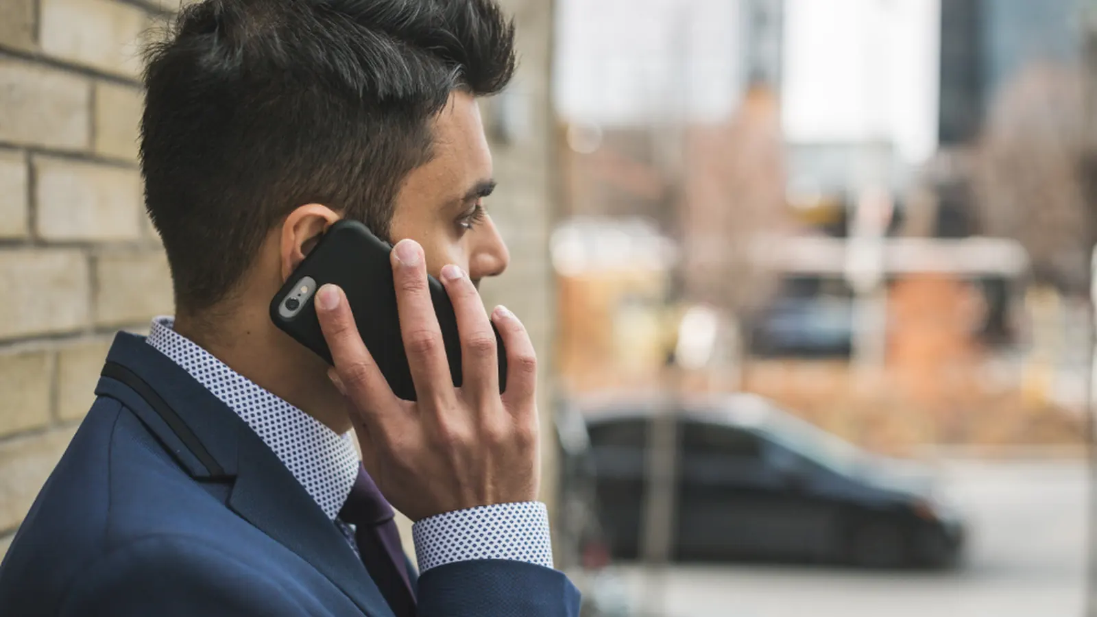 Man in a suit talking on a mobile phone outside an office