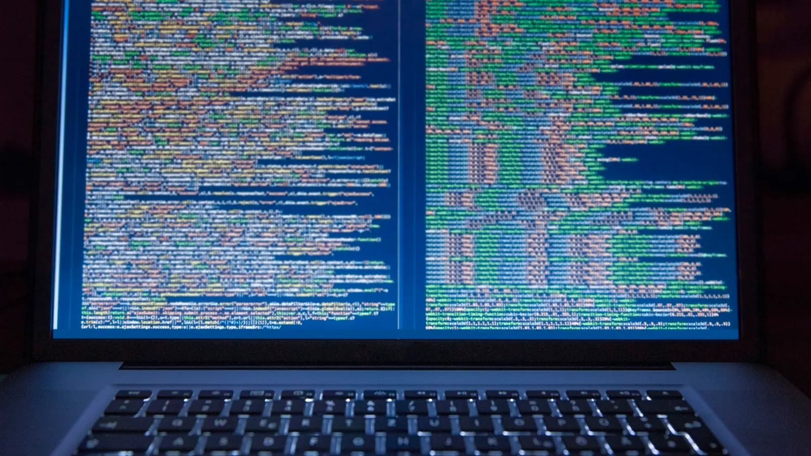 Laptop screen showing lines of code in a dark room